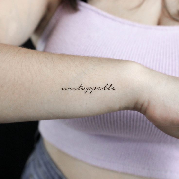 a woman's arm with the word unstoppable written on it in cursive font