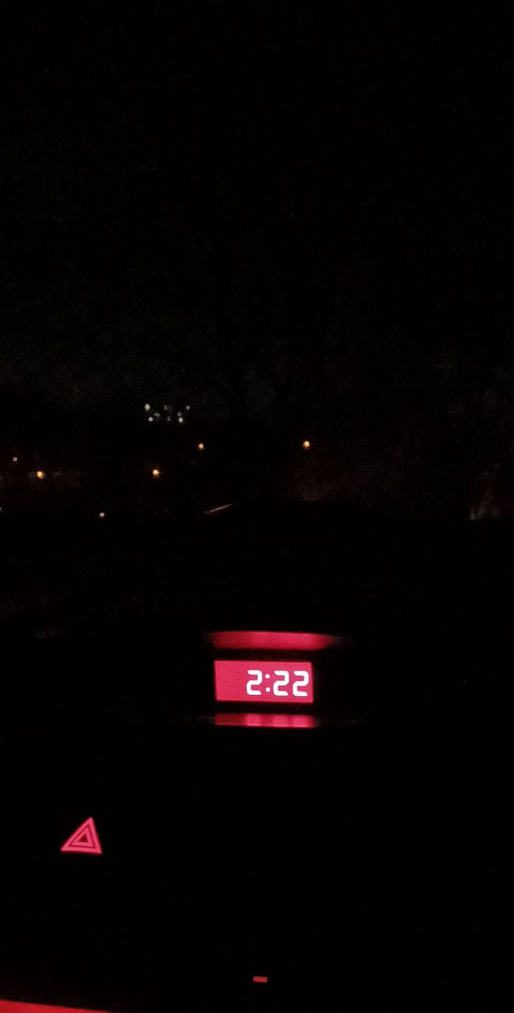 the clock is lit up in the dark with red light on it's display