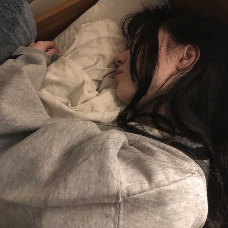 a woman laying in bed with her head on the pillow