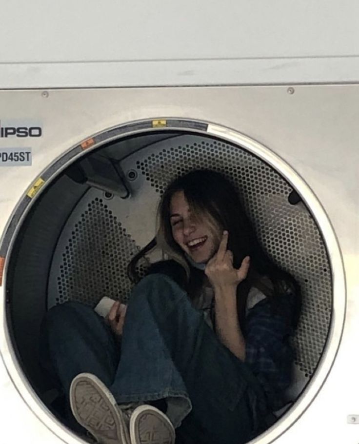 a woman sitting in a washing machine talking on the phone