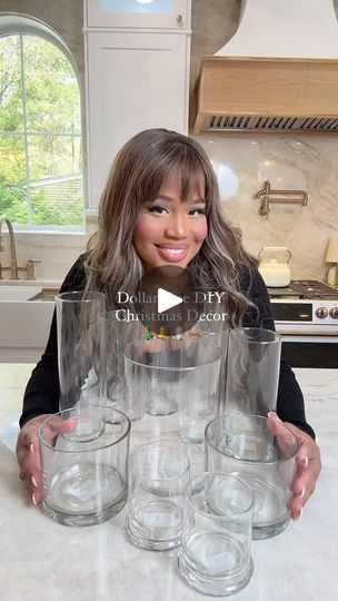 a woman standing in front of a stack of glasses on top of a kitchen counter