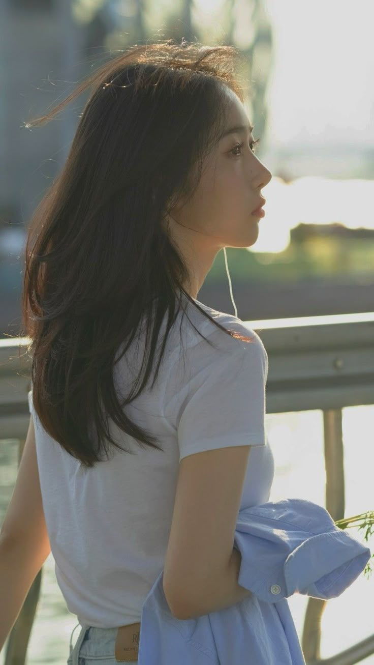 a woman with long hair is standing by the water