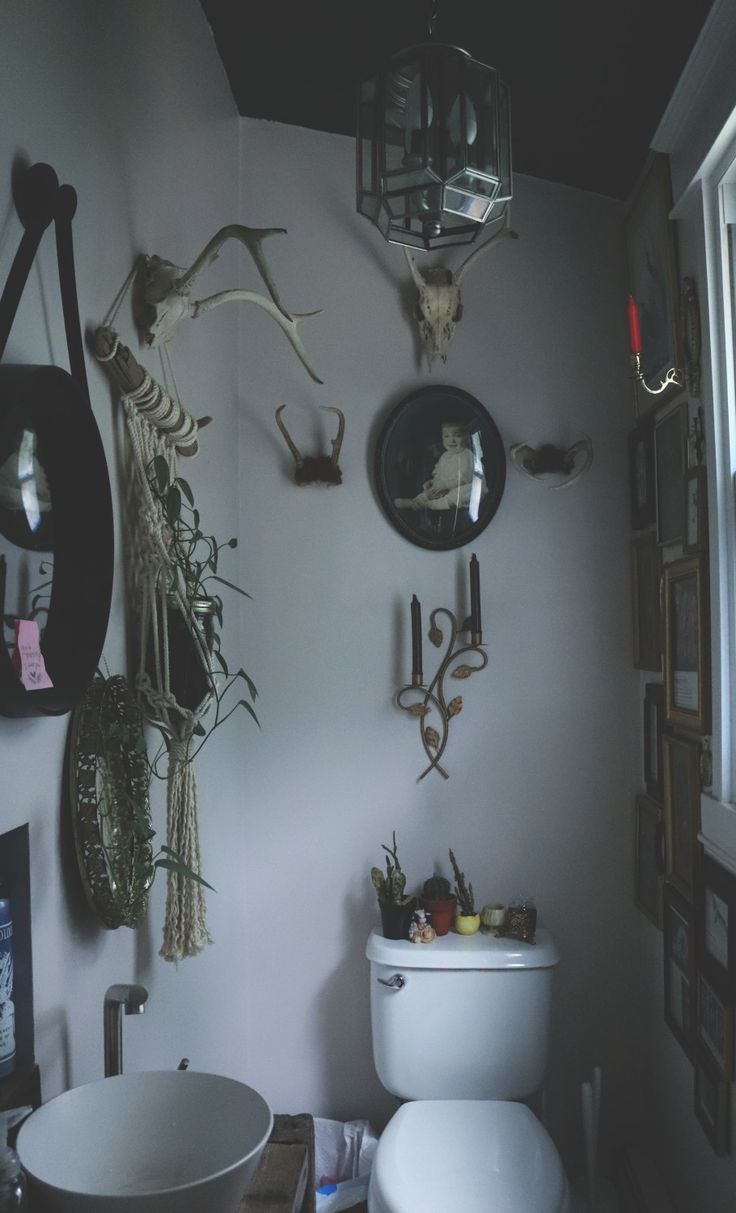 a white toilet sitting in a bathroom next to a sink under a mirror with antlers hanging on the wall