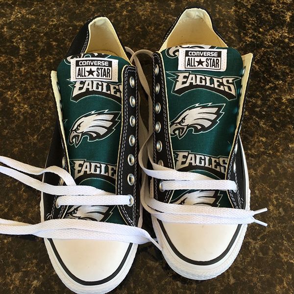 a pair of green and white sneakers with the philadelphia eagles logo on them, tied together