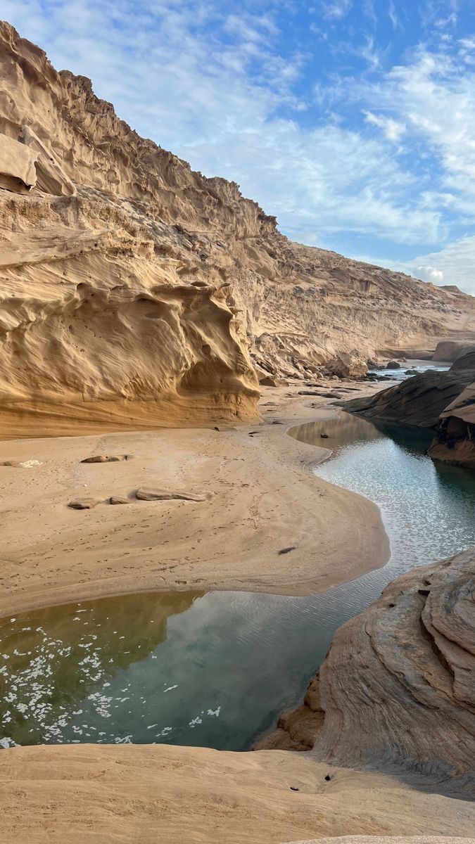 a river in the middle of a desert area with rocks and sand on both sides