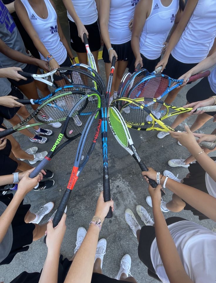 a group of people holding tennis racquets in the middle of a circle