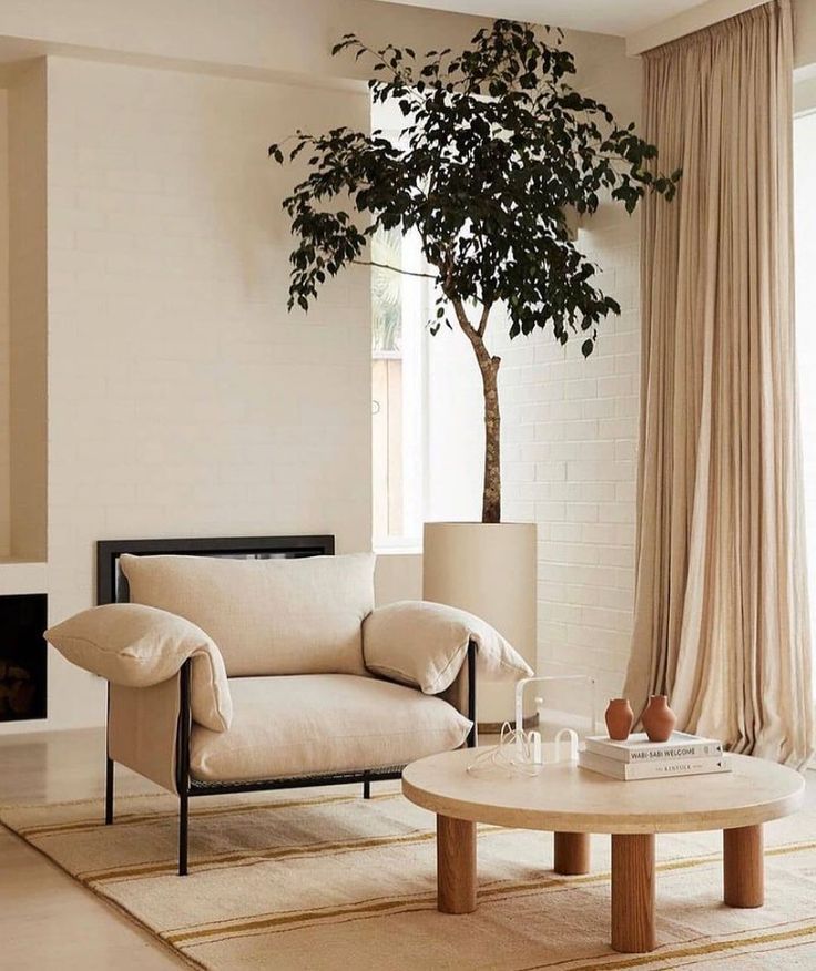 a living room with a tree in the corner next to a couch and coffee table