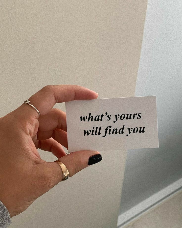 a person holding up a card with the words what's yours will find you