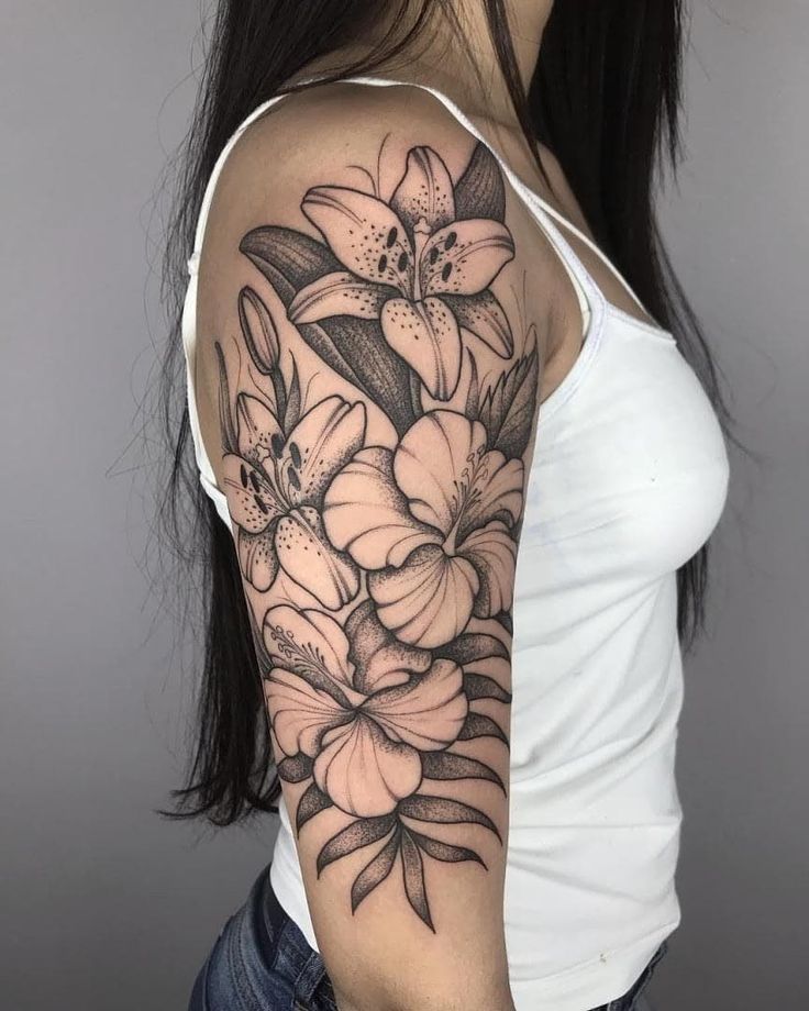 a woman's arm with flowers and leaves on the back of her shoulder, in black and white