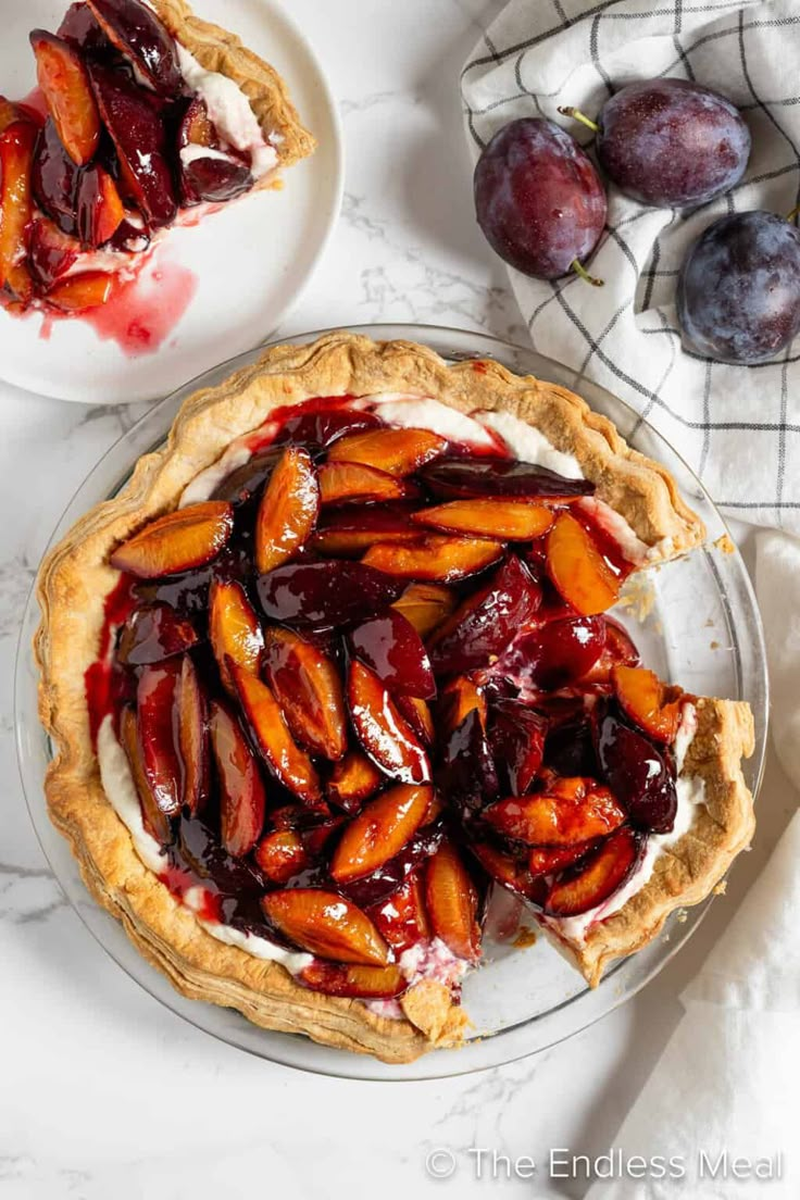 a pie with cherries and whipped cream is on a plate next to two plates