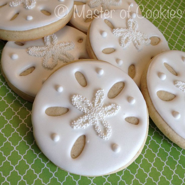 cookies decorated with white frosting and snowflakes are on a green tablecloth