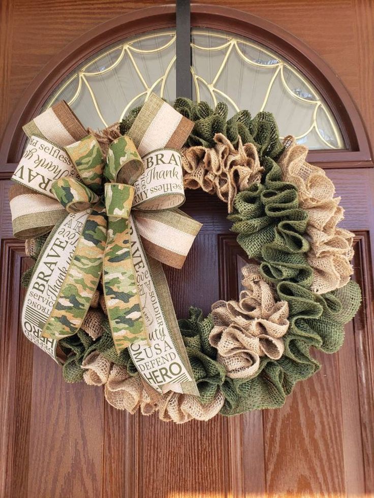 a wreath is hanging on the front door with burlocks and ribbons around it