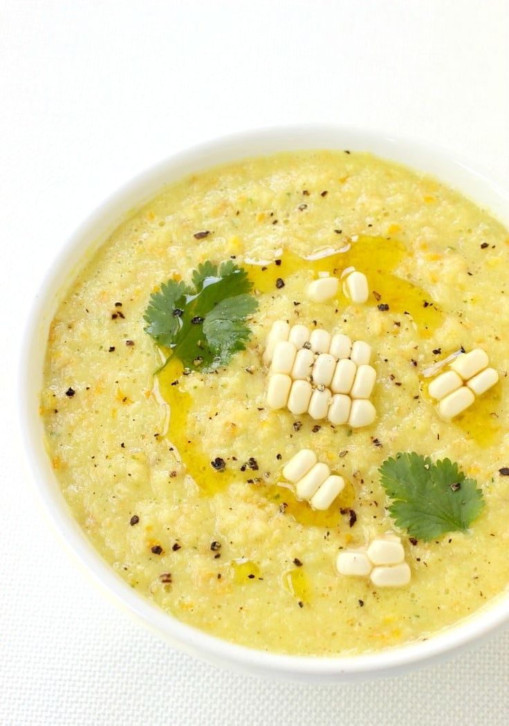 a white bowl filled with soup and garnished with corn kernels on top