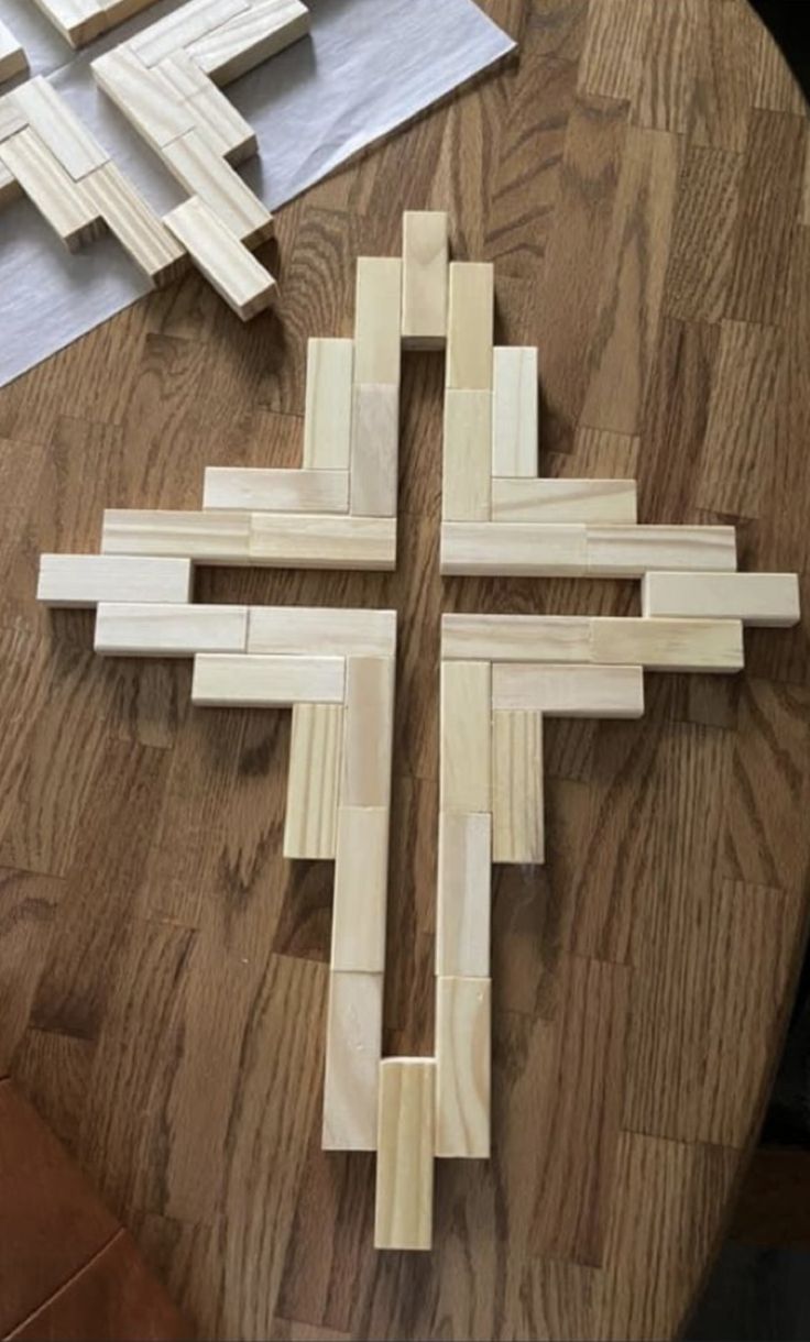 a cross made out of wood sitting on top of a wooden table next to scissors