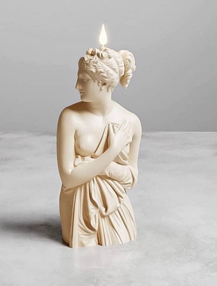 a white statue with a lit candle in it's head and hands on its chest