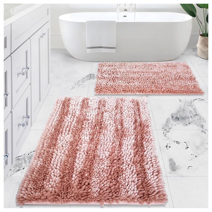 two bathroom rugs on the floor in front of a bathtub