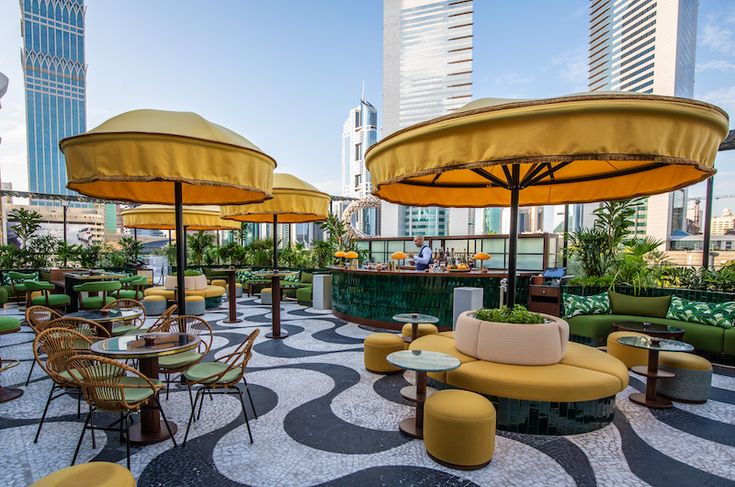 an outdoor seating area with yellow umbrellas and green couches in the foreground