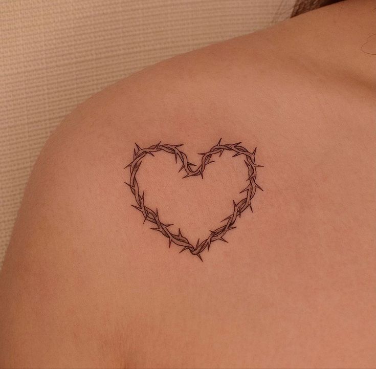 a heart shaped tattoo on the back of a woman's shoulder