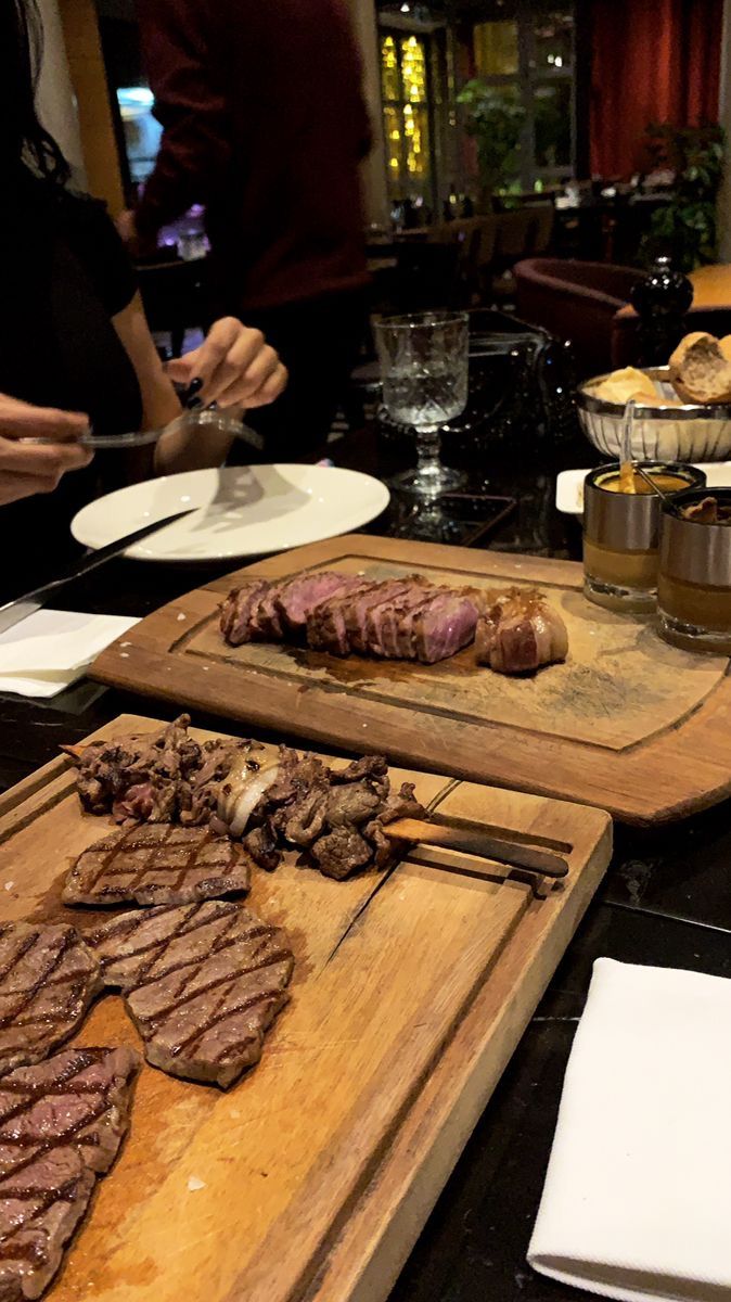 some steaks are being prepared on cutting boards with utensils in front of them