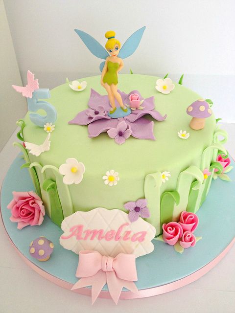 a birthday cake decorated with flowers and a tinkerbell figure