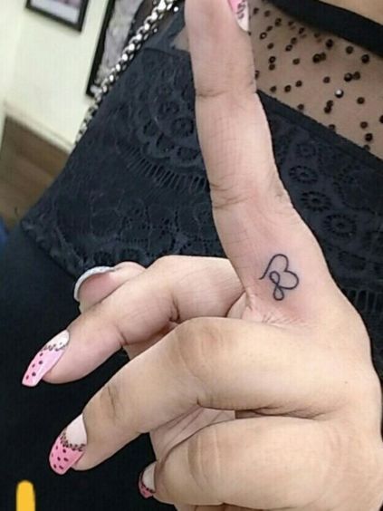 a woman with pink and white nail polish holding up her peace sign tattoo on her left hand