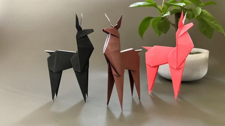 three origami deer standing next to a potted plant