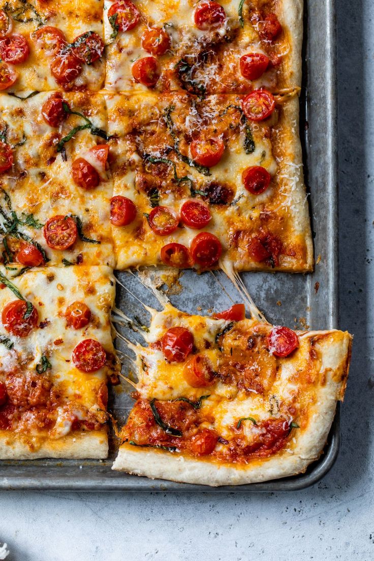 a pizza with cheese and tomatoes cut into four slices on a pan, ready to be eaten