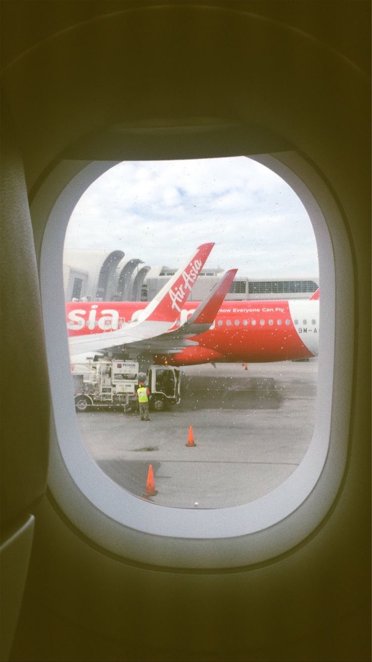 an airplane window looking out at airplanes parked on the tarmac