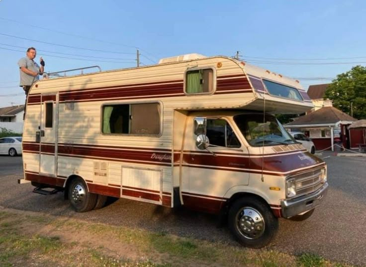 a man standing on top of an rv parked in a parking lot next to a house