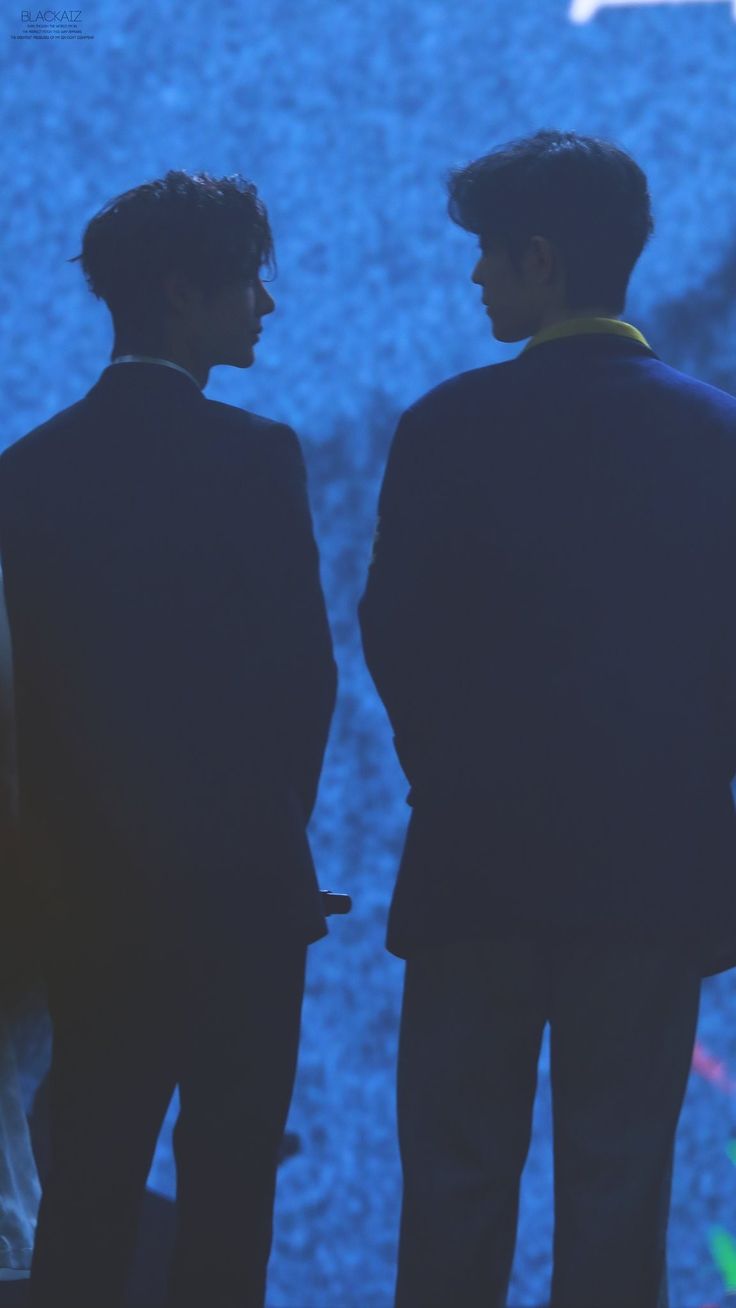 two men standing next to each other in front of a blue screen with an airplane on it