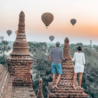 two people looking at hot air balloons in the sky