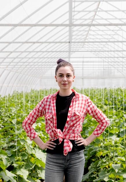 a woman standing in a greenhouse with her hands on her hips