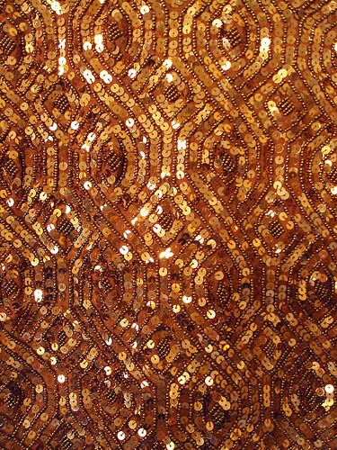 gold sequins are on the side of a brown cloth with circles and dots