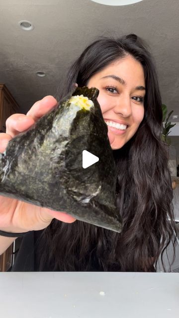 a woman holding up a piece of sushi