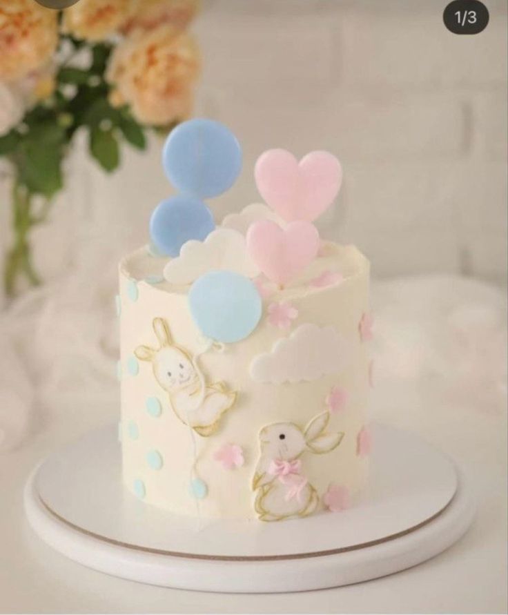 a white cake with pink, blue and yellow decorations on it sitting on a plate