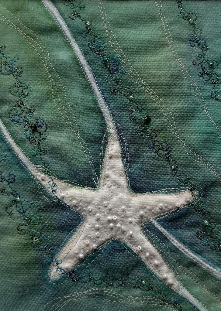 a white starfish on green fabric with beading