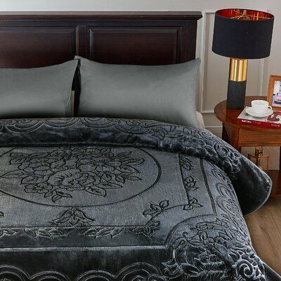 a bed with two lamps on either side of it and a black comforter in the middle