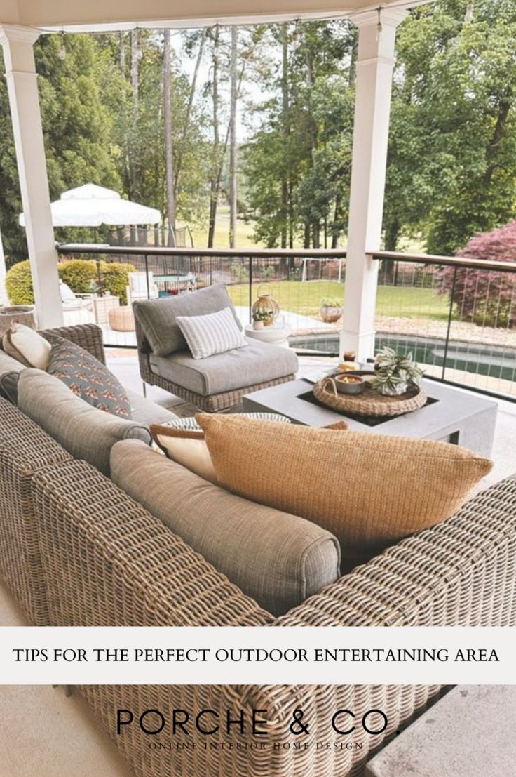 an outdoor living area with couches and tables on the porch, surrounded by trees