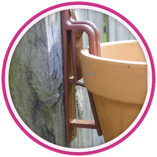 a pink circle frame with a brown planter on the side of a wooden fence