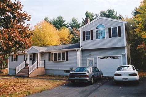 two cars parked in front of a house with trees and leaves on the ground around it