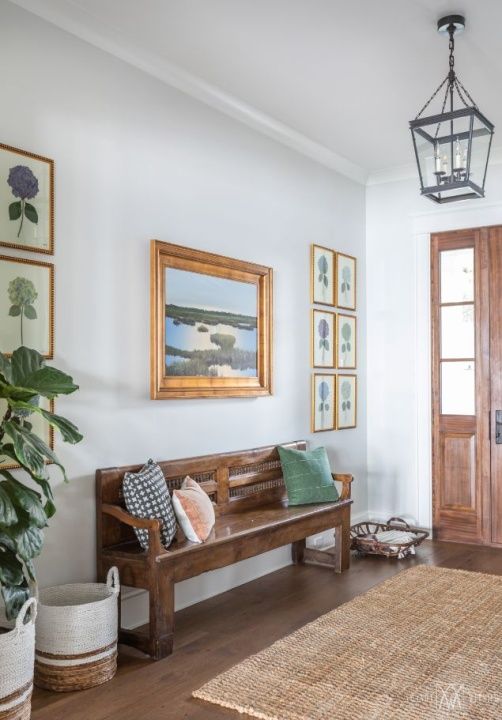 a wooden bench sitting in the middle of a living room next to a door and potted plant