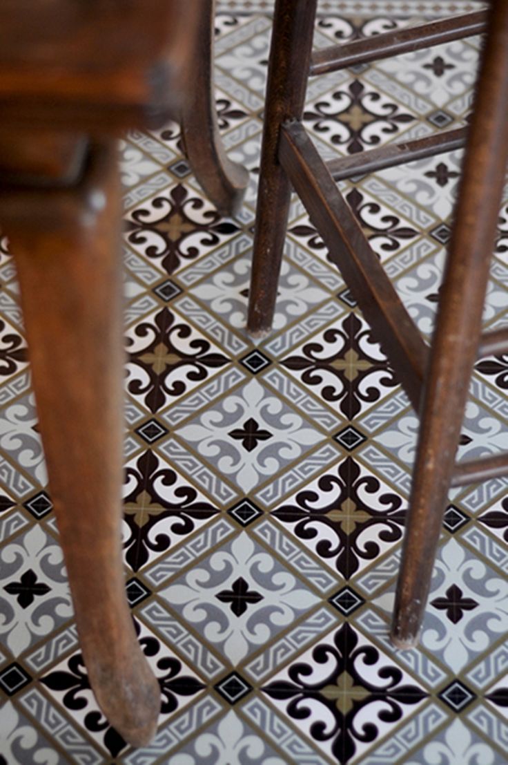 two wooden stools sitting next to each other on a tiled floor with black and white designs