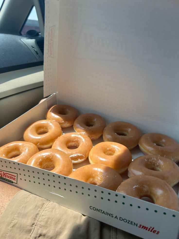 a box full of glazed donuts sitting on the back seat of a car,