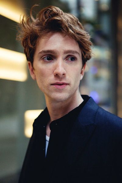 a young man is standing in front of a building and looking off into the distance