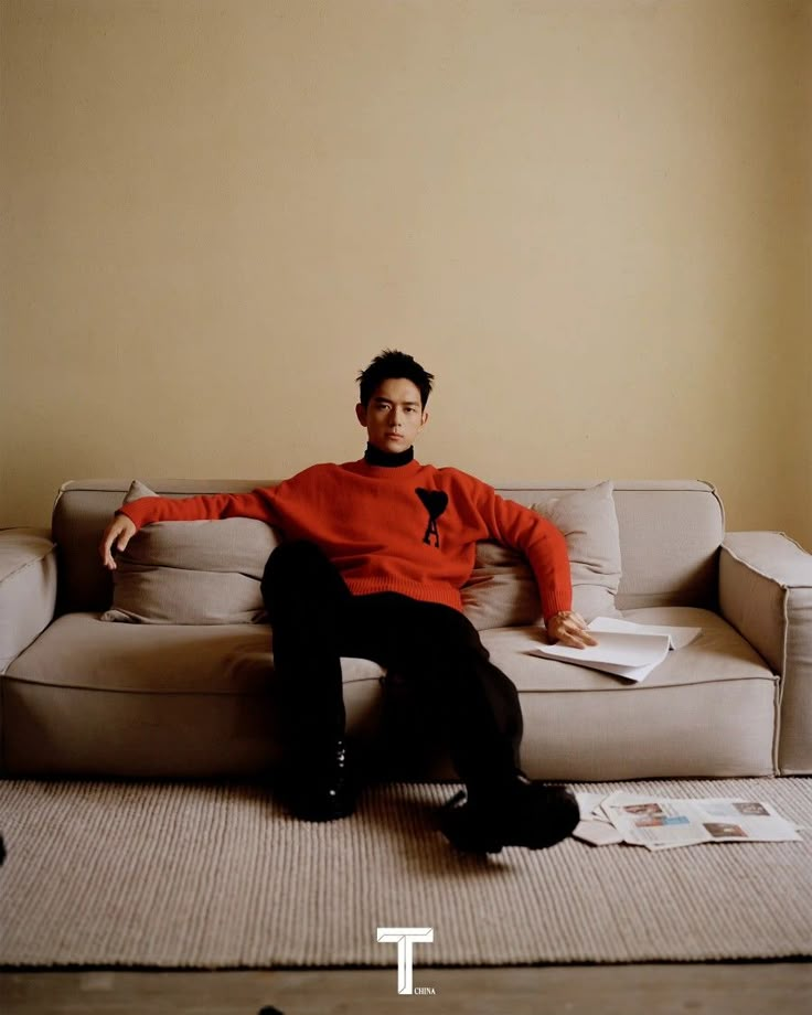 a man sitting on top of a couch in front of a wall with the words t above it