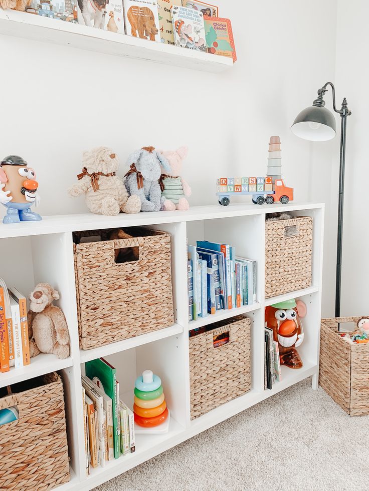 a white bookcase with baskets and stuffed animals on it in a child's room