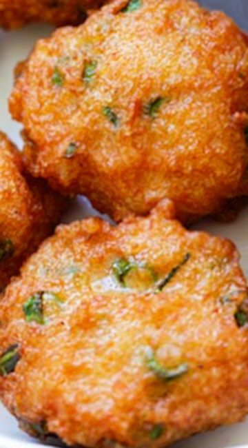 some fried food on a white plate with green garnishes and seasoning