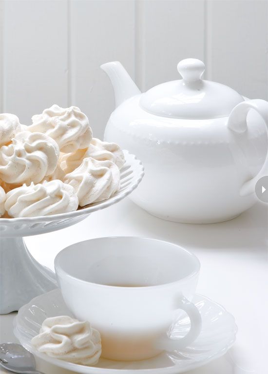 a bowl of meringue next to a teapot and cup on a saucer