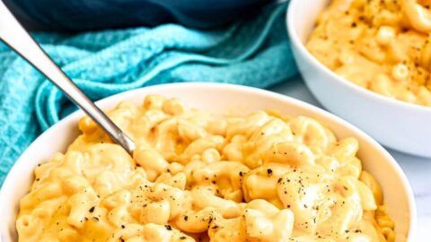 two bowls filled with macaroni and cheese on top of a white tablecloth