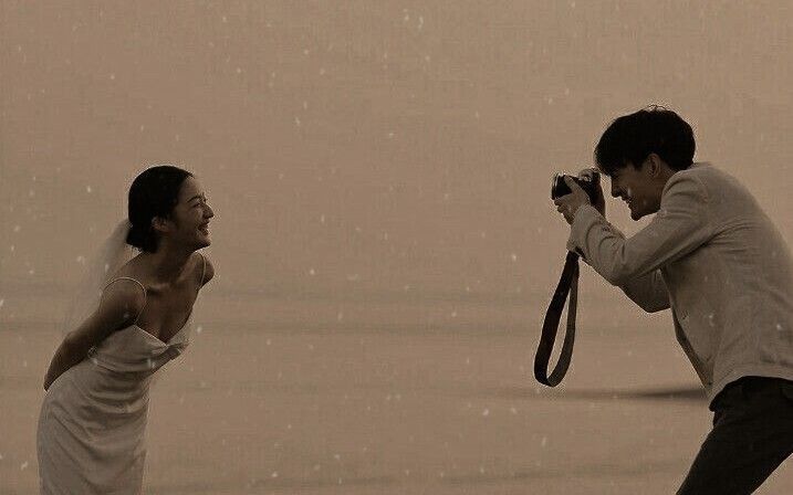 a man and woman taking pictures in the rain